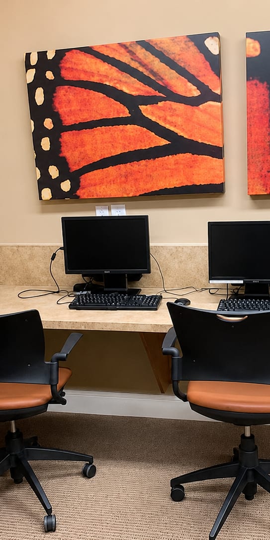 A room with a desk and chairs and two paintings on the wall.
