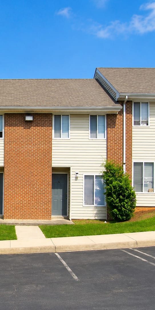 A row of townhouses with a parking lot in front.