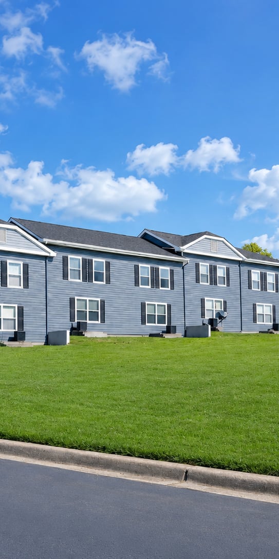 A row of houses with a blue sky and clouds in the background.