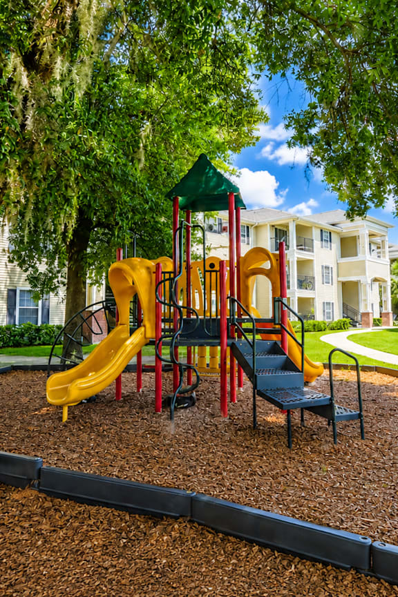 A playground with a yellow slide and a green canopy.