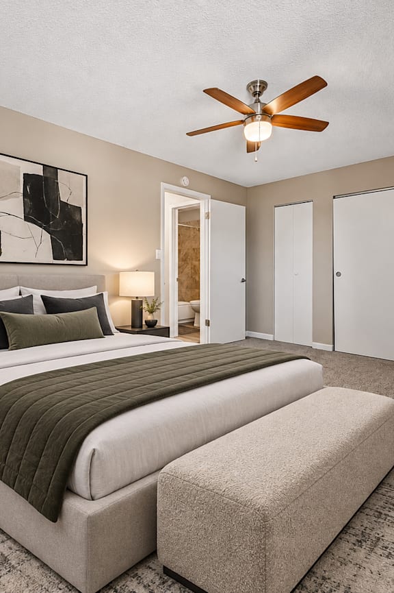 A bedroom with a large bed and a ceiling fan.