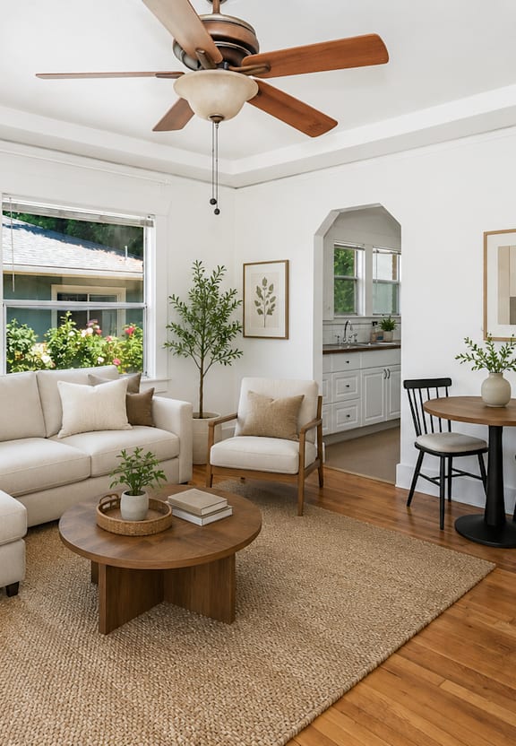 A living room with a white couch, a wooden coffee table, and a ceiling fan.