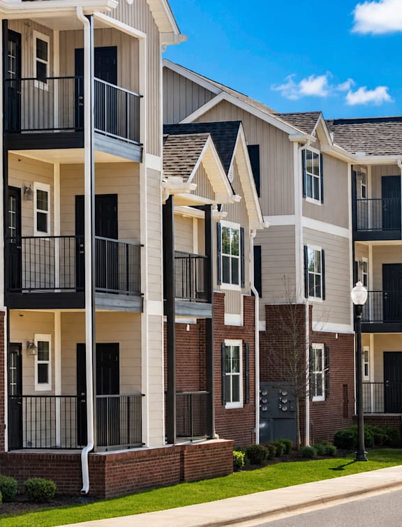 A row of modern apartment buildings with balconies and black railings.