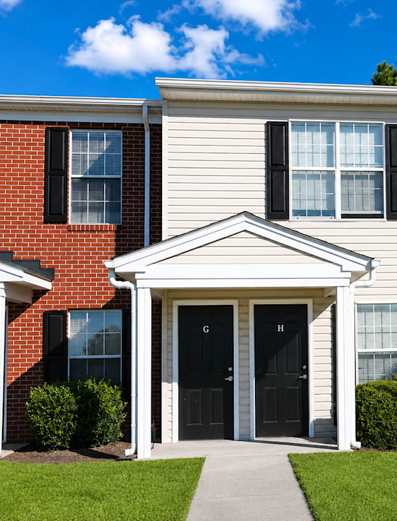 A house with a red brick section and a white siding section with a black door and windows.