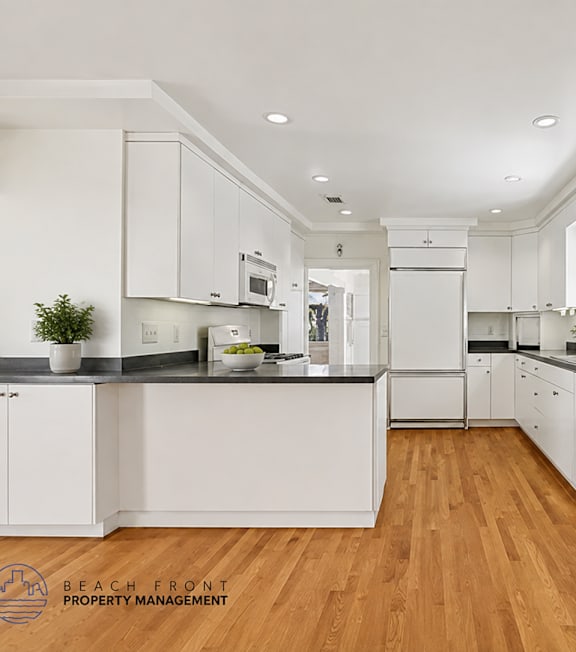 A modern kitchen with white cabinets and wooden floors.