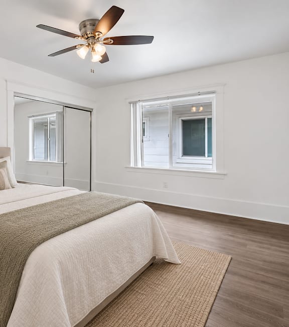 A well-lit bedroom with a large bed and a painting on the wall.