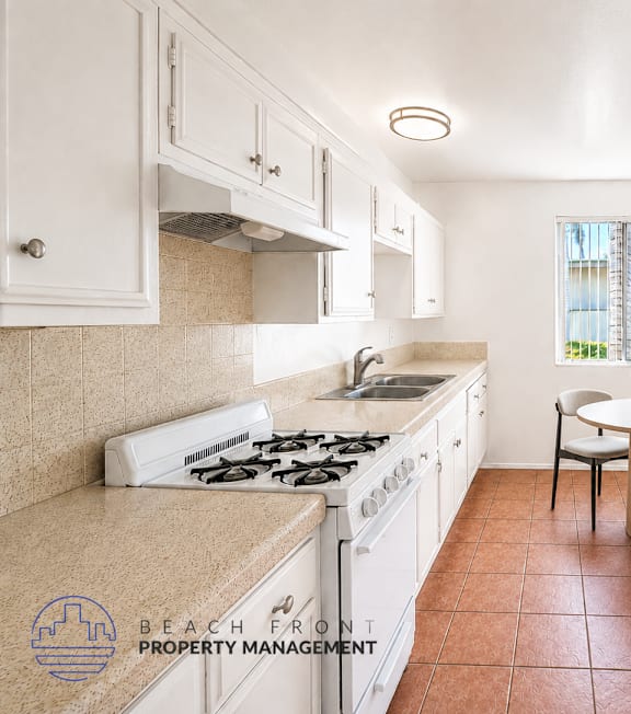 A kitchen with a stove top oven and a dining table with chairs.