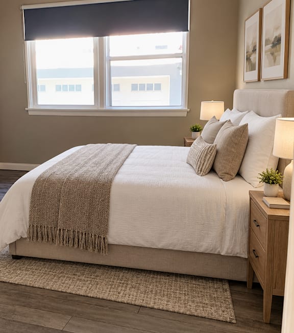 A well-lit bedroom with a large bed and a painting on the wall.
