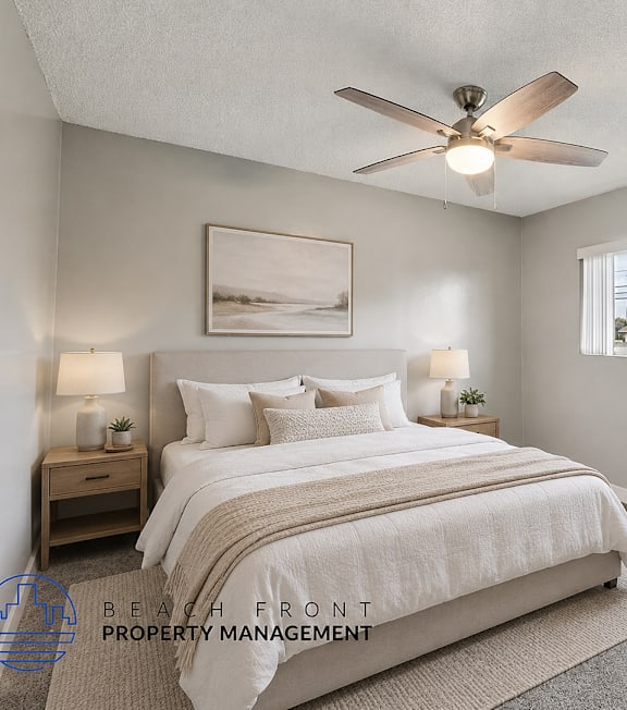 A room with a ceiling fan and a view of the beach through the window.