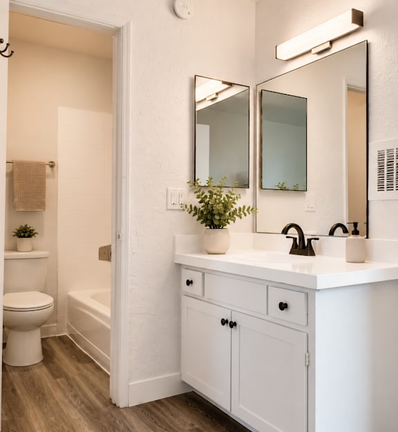 A white bathroom with a toilet, sink, and mirror.