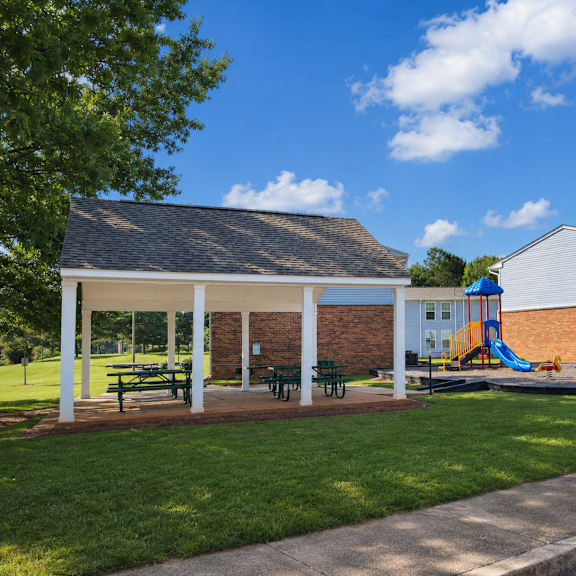 A playground area with a slide and picnic tables is located in front of a building.