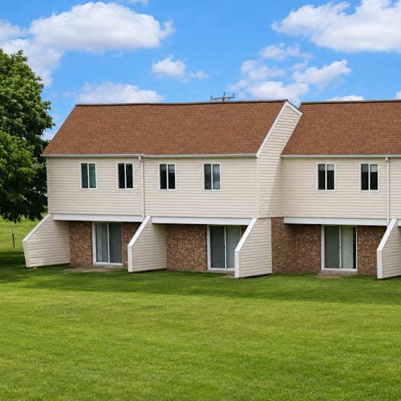 A white building with a brown roof and a green lawn in front.