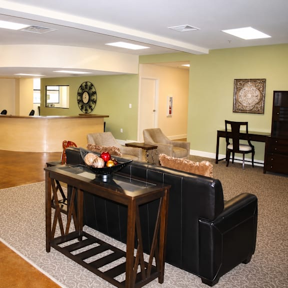 A living room with a black leather couch and a wooden coffee table.