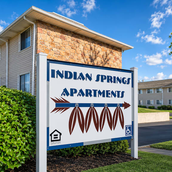 A sign for Indian Springs Apartments stands in front of a building.