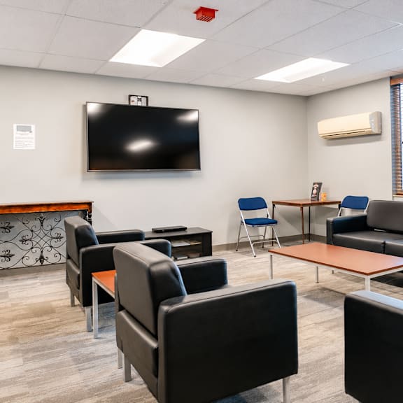 A conference room with a television on the wall and comfortable seating.