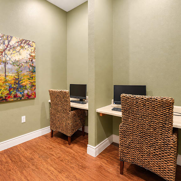 A room with a painting of a tree and three chairs.