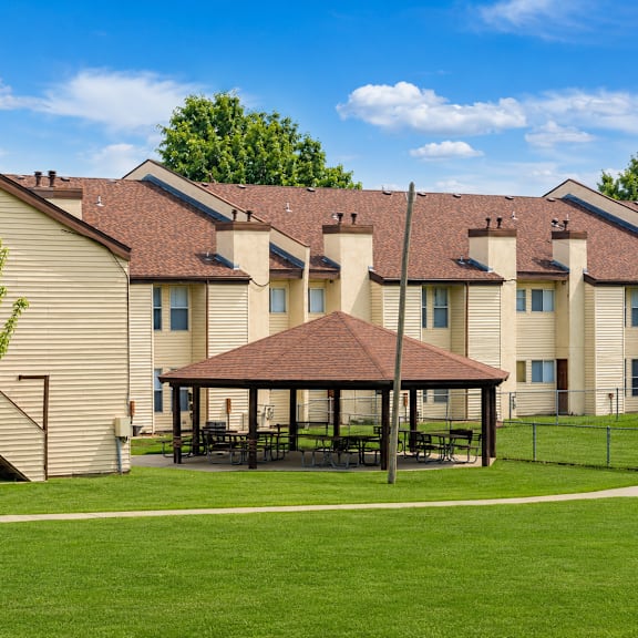 A tree stands in front of a building with a covered patio.