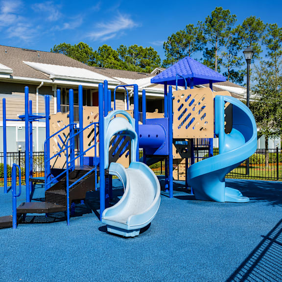A playground with a blue slide and a wooden structure.
