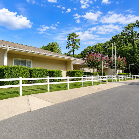 a yellow house with a white fence and green grass