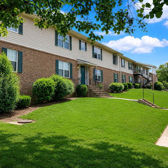 Apartment building with green bushes in front.