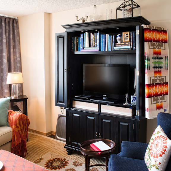 A living room with a black entertainment center and a blue chair.