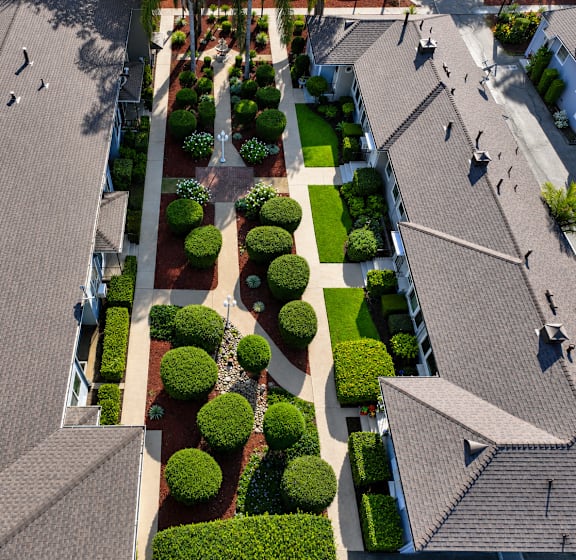 A bird's eye view of a residential area with houses and well-manicured gardens.
