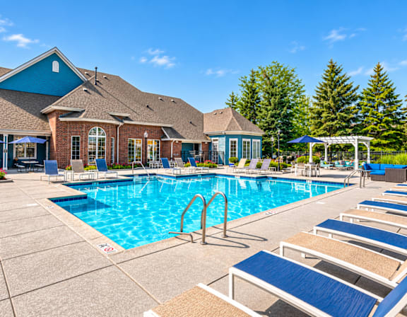 A large swimming pool with lounge chairs and a building in the background.