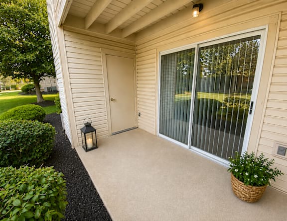 A lantern sits on a concrete patio outside a house.