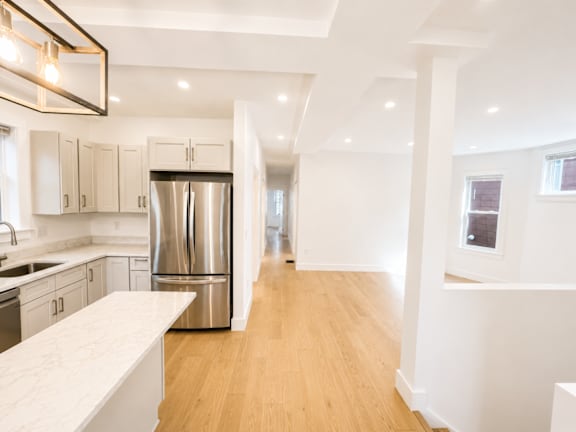 A modern kitchen with a stainless steel refrigerator and wooden floors.