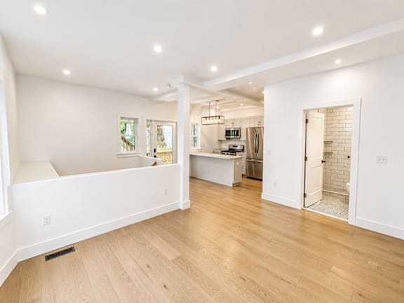 A spacious kitchen and living room with wooden floors and white walls.