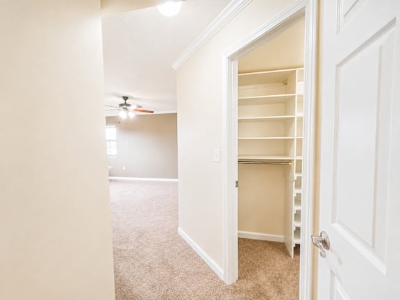 A white door is open to a room with a ceiling fan.