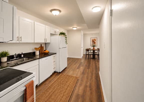 A kitchen with white cabinets and a black counter top.