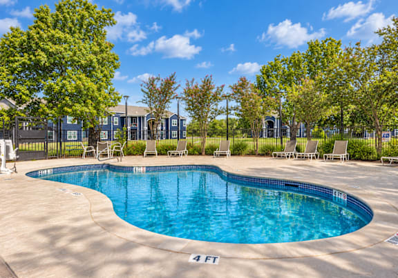 A swimming pool surrounded by a fence and trees.