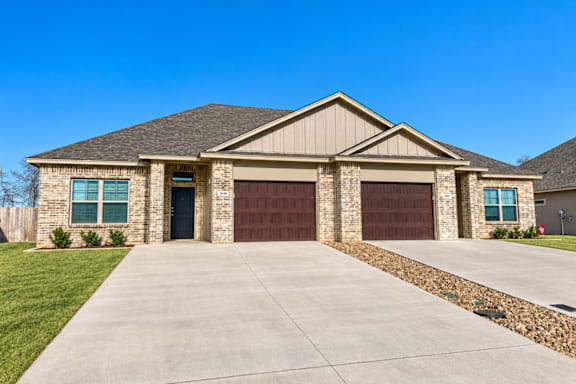 A house with a brown garage door and a grey roof.