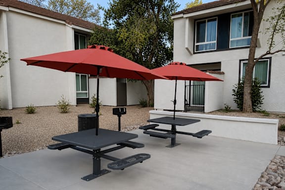 A red umbrella is on a table outside a house.