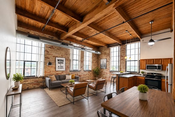 Rendering of a loft living area and kitchen with exposed brick, tall windows, and a wood-beam ceiling