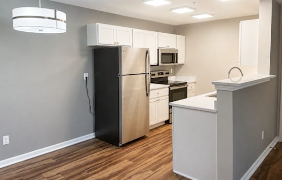A kitchen with white cabinets and a black refrigerator.