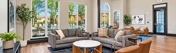 A living room with a grey couch, brown chairs, and a black coffee table.