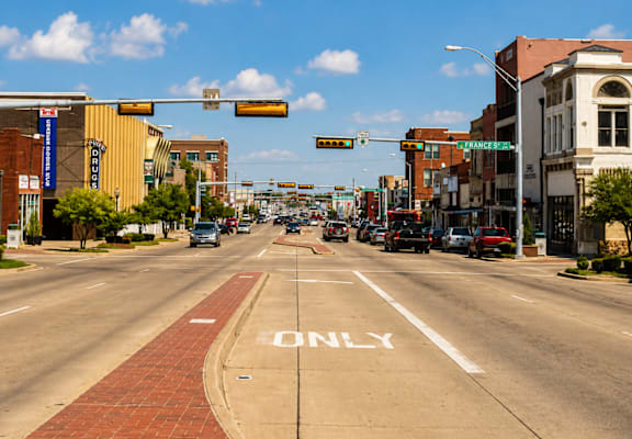 A city street with a red brick sidewalk and a white line painted on the road that says "ONLY".