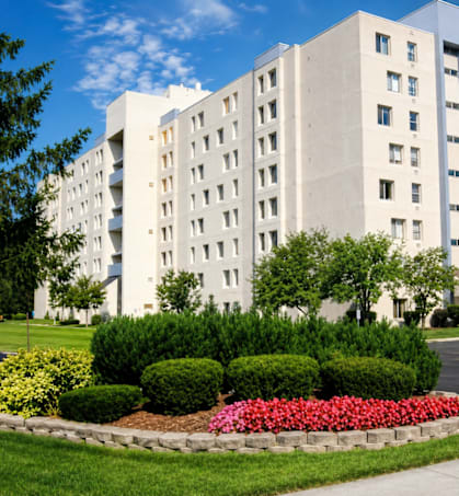 A large white building with a flower bed in front.
