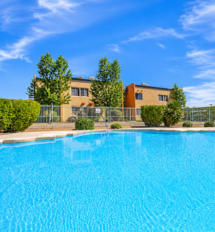 A swimming pool in front of a building with a fence around it.