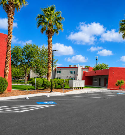 A red building with palm trees in front of it.
