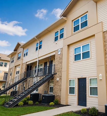 A beige apartment building with a black door and a black staircase.