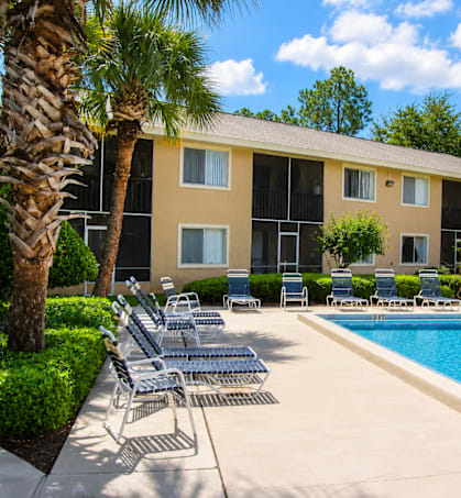 A pool area with chairs and a building in the background.