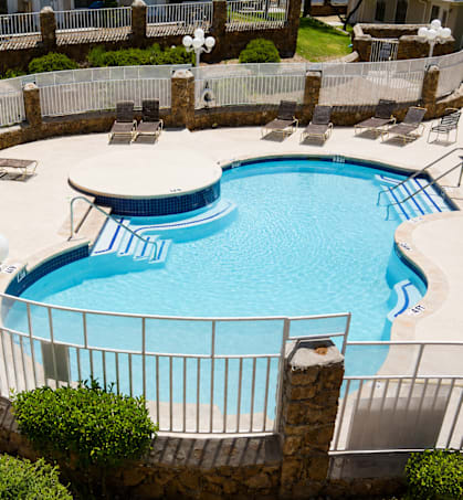 A round swimming pool surrounded by a fence and a stone wall.