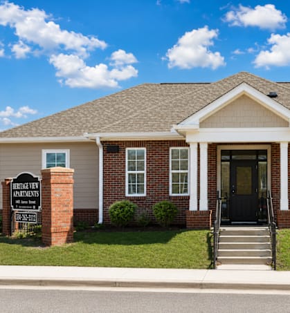 A brick building with a black door and a sign in front.