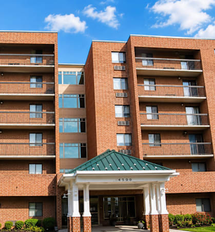 A large brick building with a green roof and a covered walkway entrance.