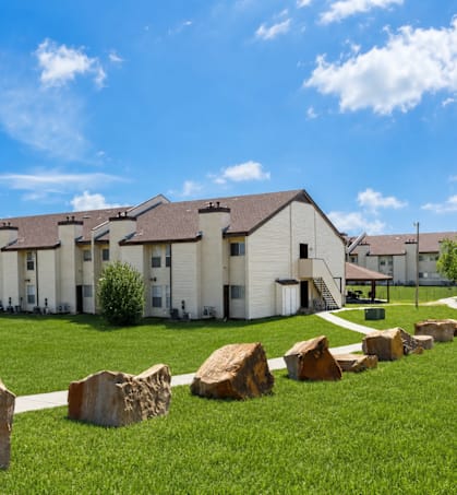 A row of houses with a grassy front yard and large rocks in the foreground.