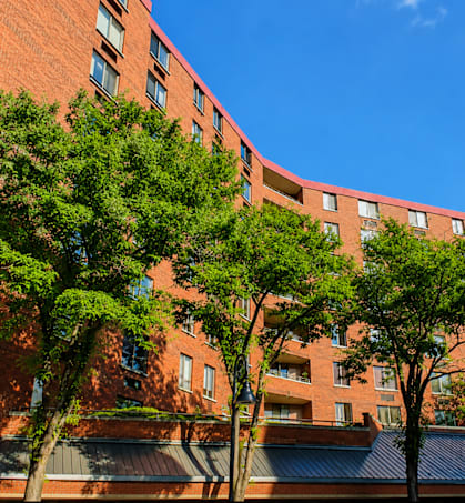 A red brick building with trees in front.