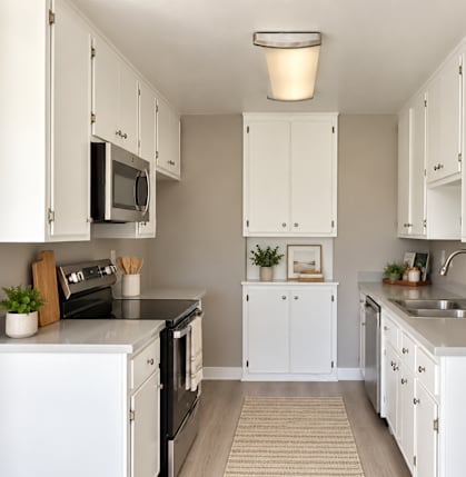A kitchen with white cabinets and appliances.
